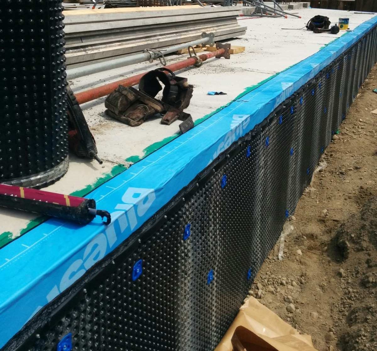 Peel-and-stick membrane and dimpled drainage layer on a commercial foundation